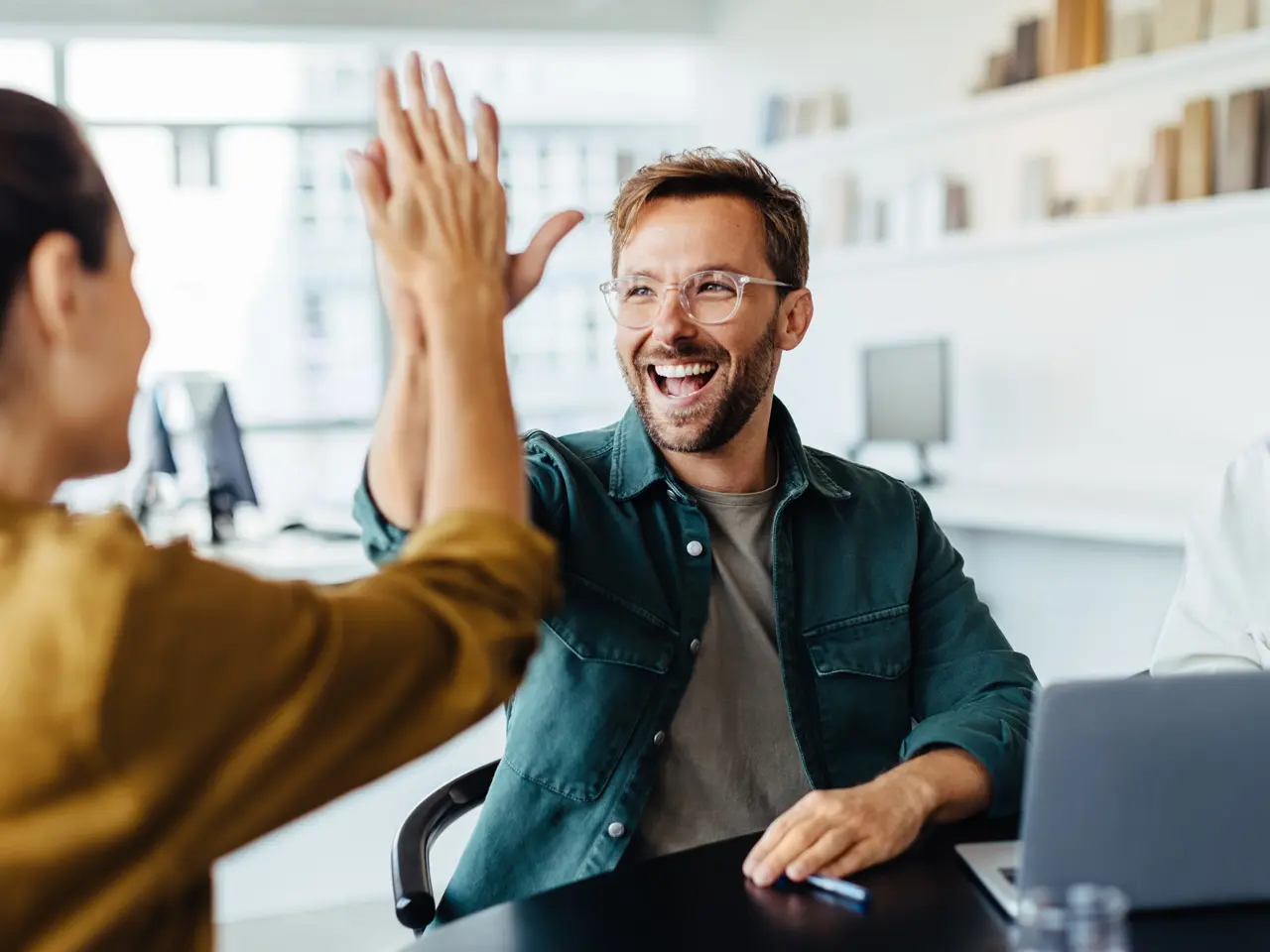 Co-workers high-fiving during a successful project meeting, representing long-term EPM implementation methodology and team ownership